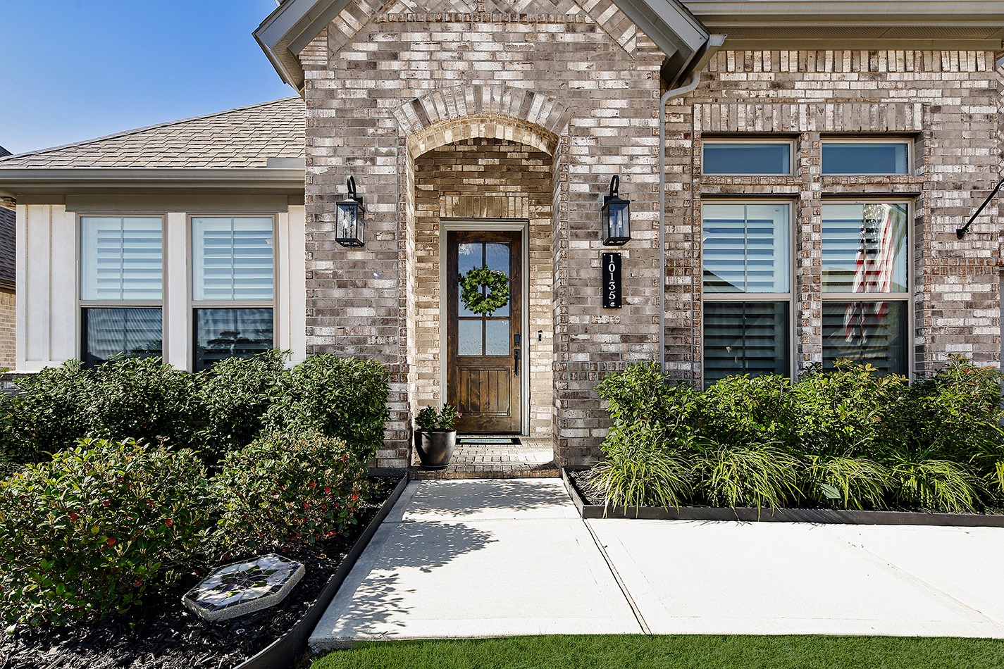 Pristine landscaping adds color, texture, and softness along the front facade, enhancing the property's overall welcoming curb appeal.