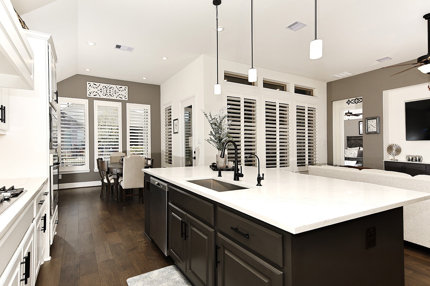 The kitchen island features rich-toned cabinetry that complements the darker wall color and beautiful wood flooring throughout the space.