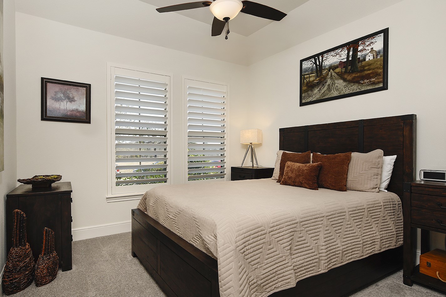Bedroom three has soft neutral colors, plantation shuttered windows, and is spacious in size for a large bed and dressers.
