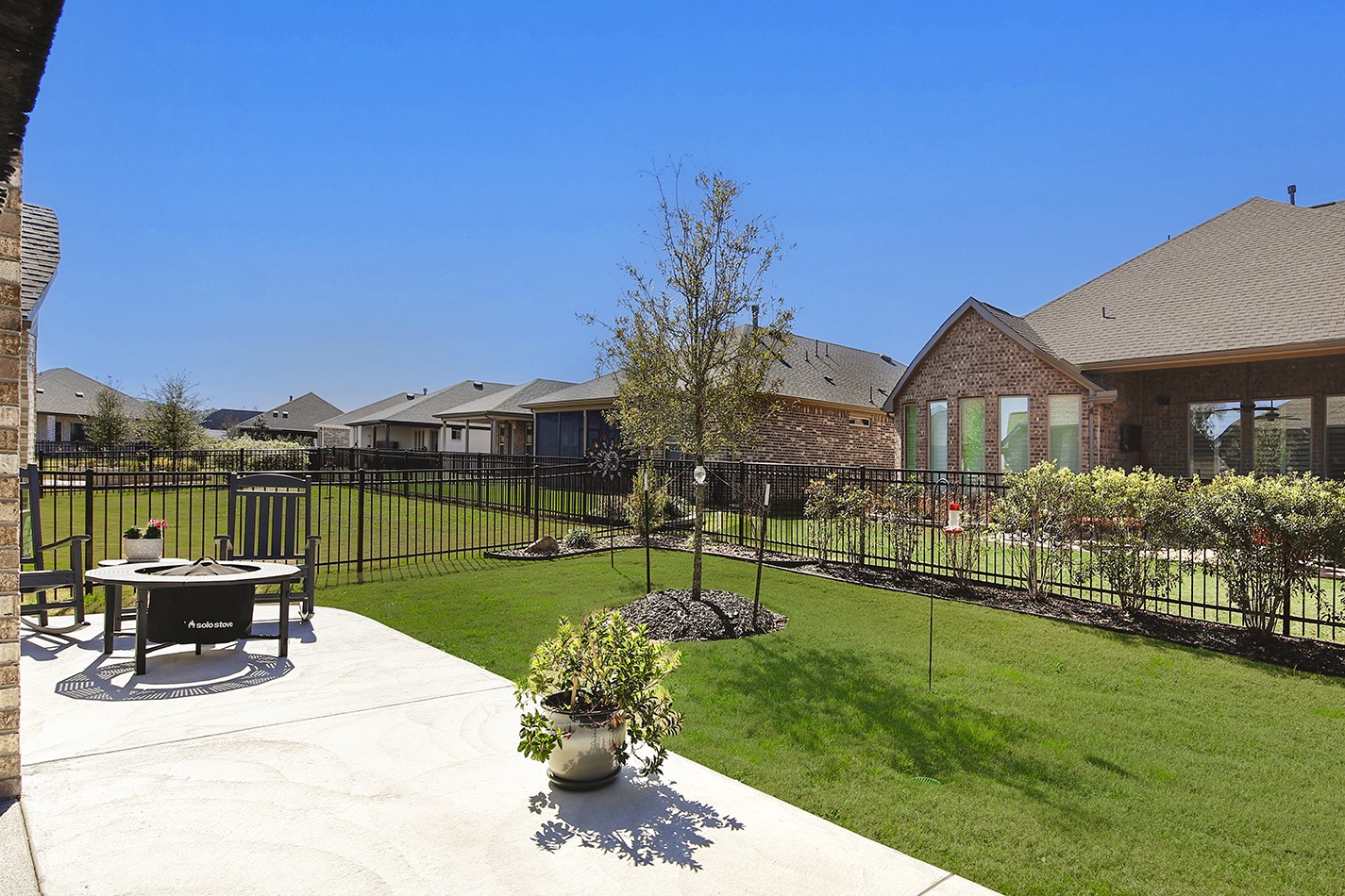 Extended concrete patio perfect for a firepit, rocking chairs, and sun-loving potted plants.