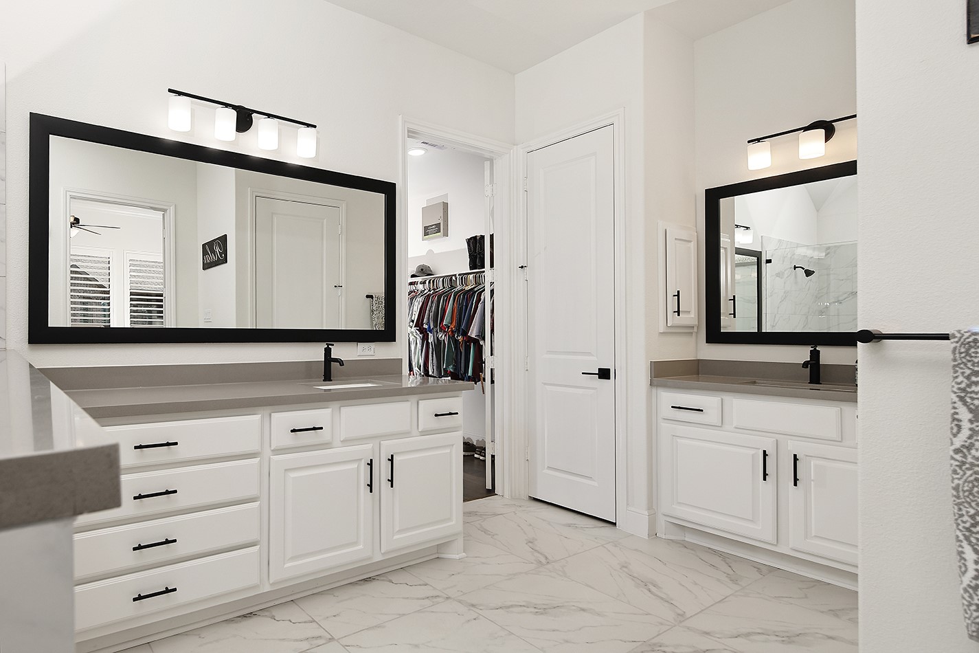 The primary bath has a highly desirable layout with separate vanity areas, offering ample counter and cabinet storage accented by modern black pulls, fixtures, and sleek mirrors.