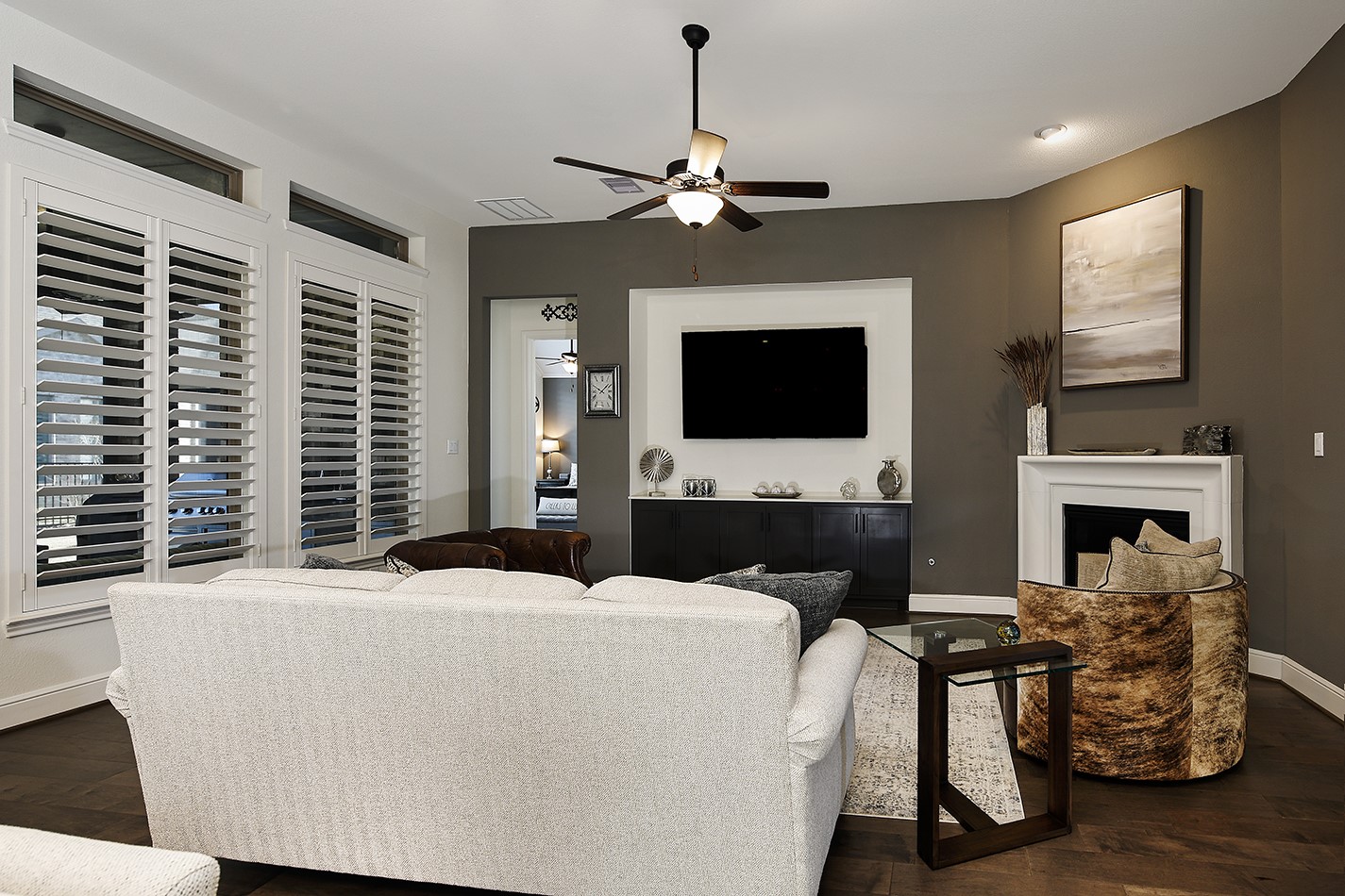 This family room features a sophisticated, high-end aesthetic with dramatic, rich wall tones that beautifully contrast the modern white fireplace mantle. The built-in recessed niche for the television and cabinetry offers a seamless, space-saving design.