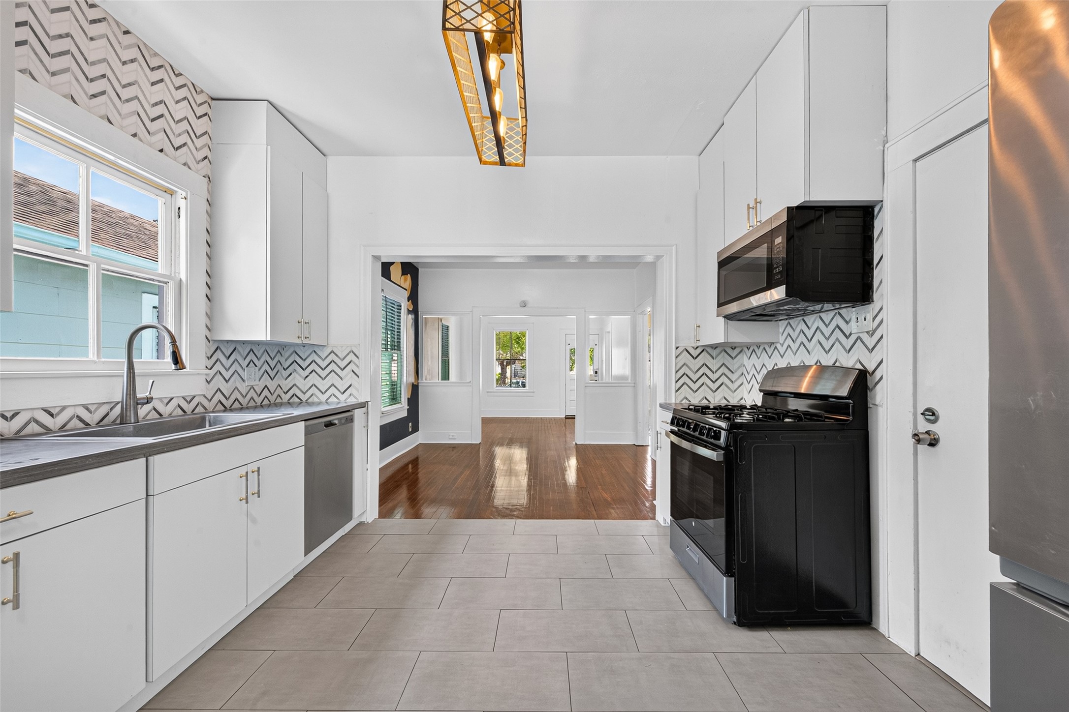 KITCHEN WITH LOTS OF NATURAL LIGHT, CORIAN TOPS, TILE FLOOR FOR EASY CLEANING, AND CLEAN WHITE CABINETS