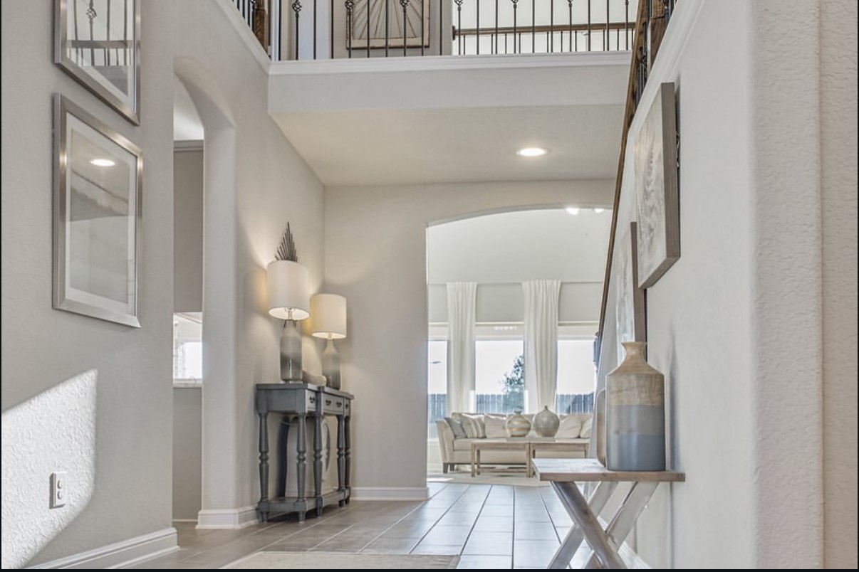 Elegant entryway leading to a bright living area, featuring high ceilings and natural light streaming through large wall of windows. Elegant entryway leading to a bright living area, featuring high ceilings and natural light streaming through large wall of windows.