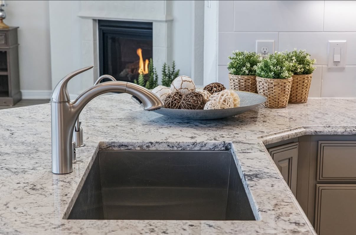 The kitchen space show cases a sleek stainless steel faucet and granite countertops, complemented by a cozy fireplace.