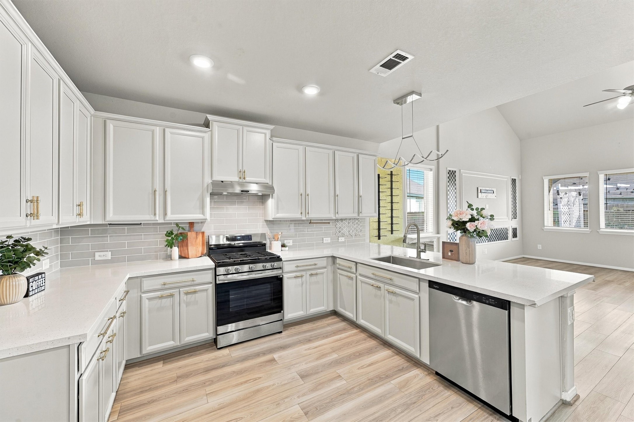 Bright kitchen featuring white cabinetry, a spacious center island, and an open layout overlooking the living area.