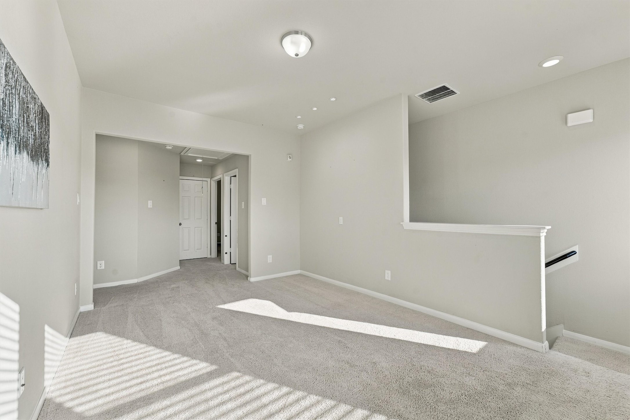 Bright upstairs family room with multiple windows and neutral carpeting.