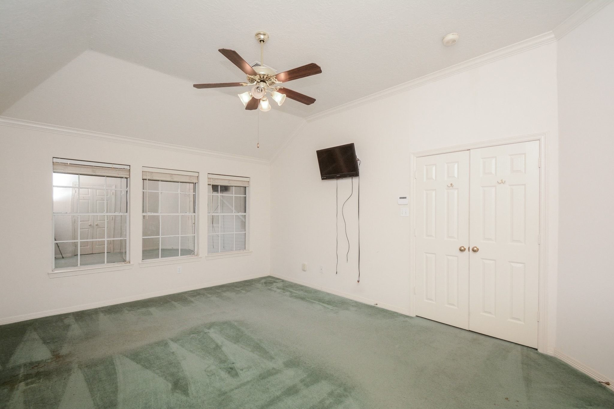 View of primary bedroom with wall of windows overlooking the backyard