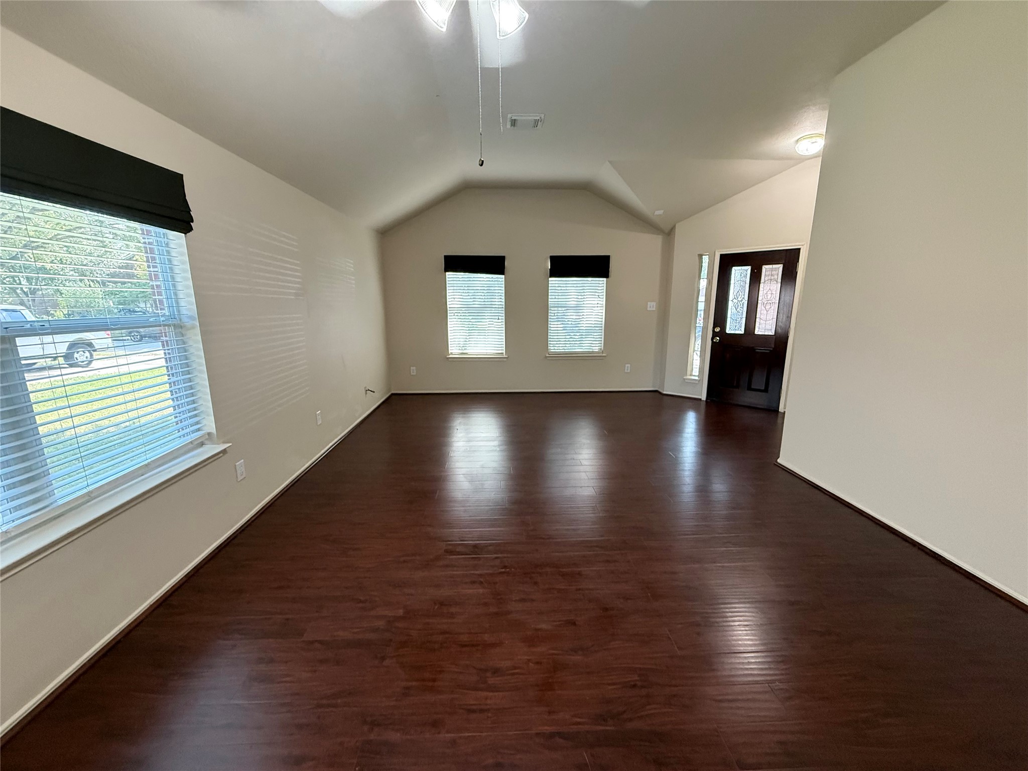 Step into this inviting, spacious living area with elegant dark wood flooring and abundant natural light, perfectly framing your front door as a welcoming centerpiece.