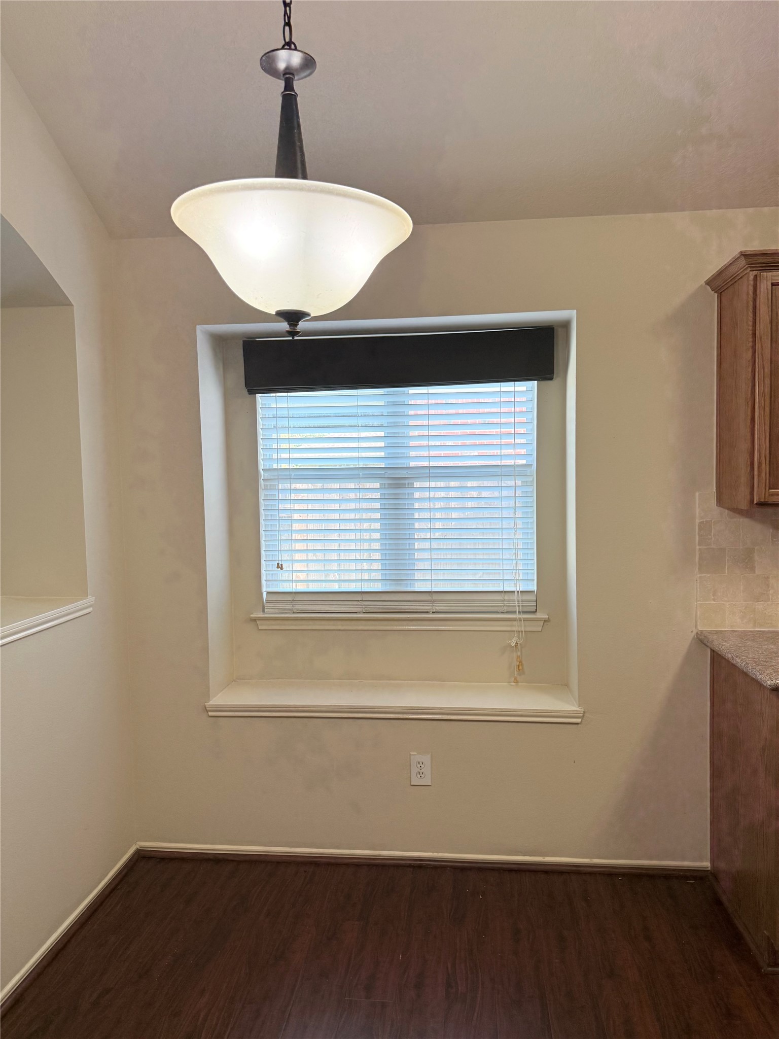 Cozy dining nook with a large window seat, elegant pendant lighting, and warm wood flooring, perfect for intimate meals.