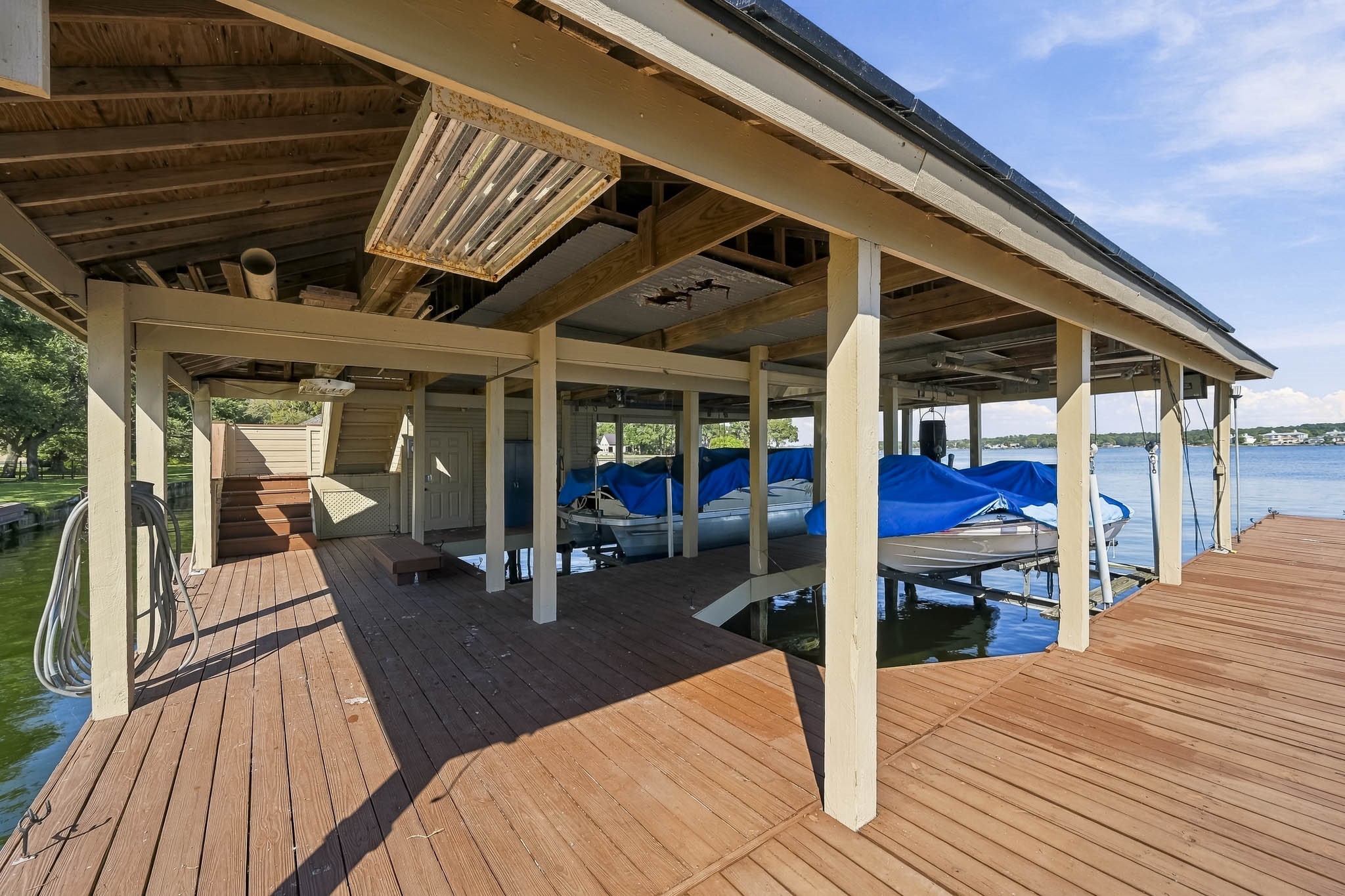 Take lake living to another level! Stairs lead to the boathouse's upper sundeck, offering an elevated space to relax and enjoy the waterfront setting. Boats not included.