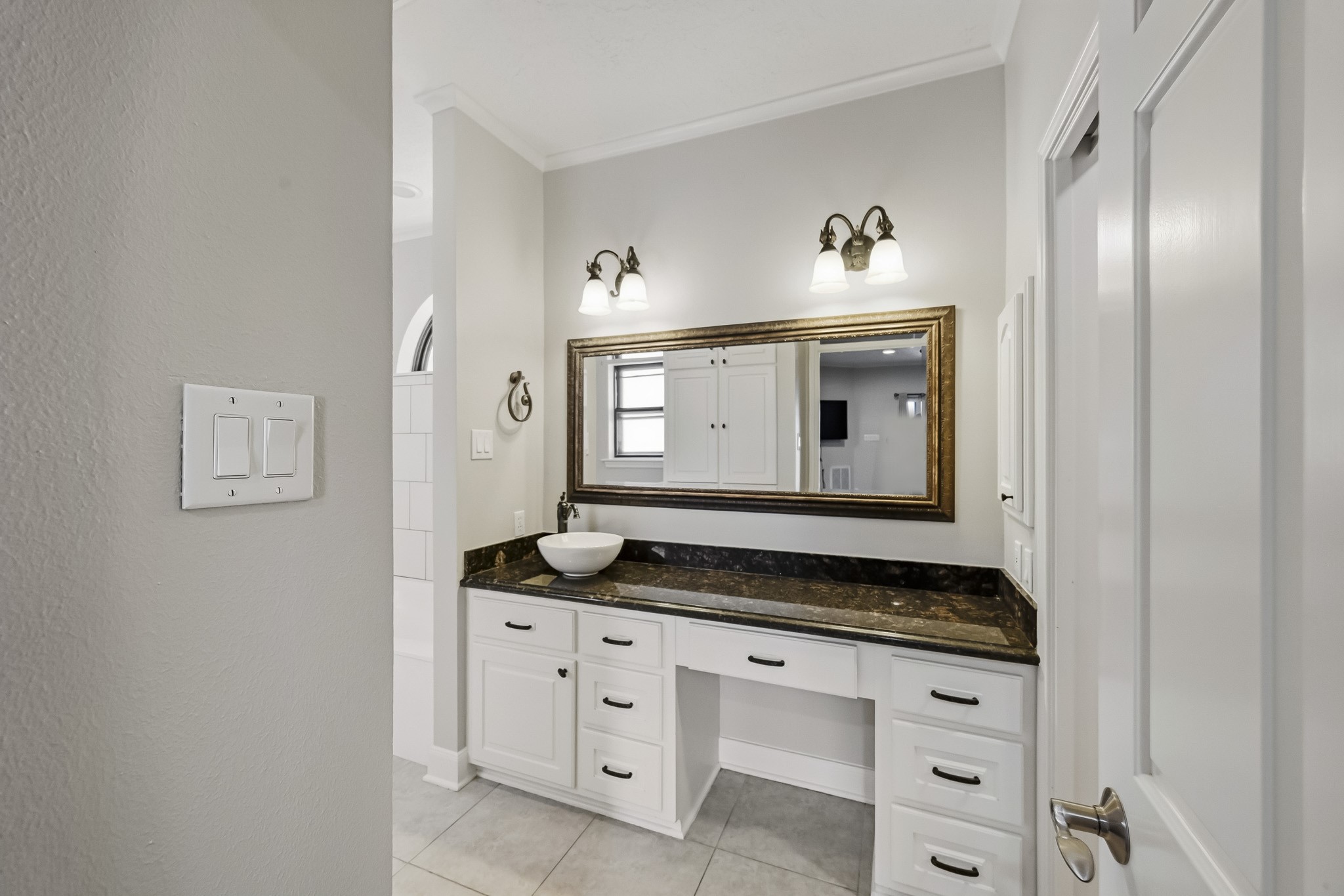 One of TWO primary bathrooms! This beautifully appointed space features an extended granite vanity, vessel sink, framed mirror, decorative lighting and abundant cabinet storage.