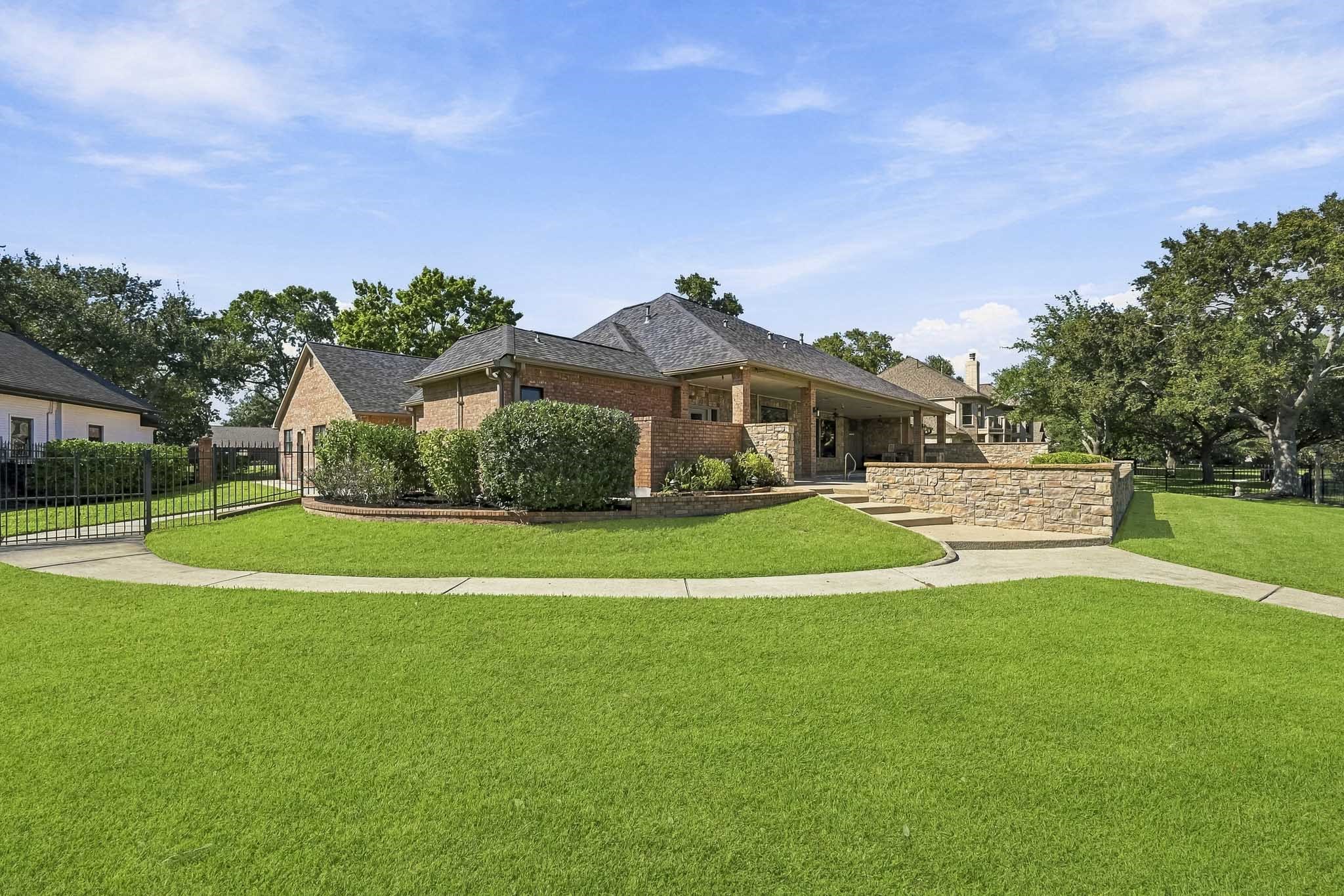 Beautifully maintained grounds surround this custom waterfront home, with a curved walkway leading toward the pool and outdoor living areas.