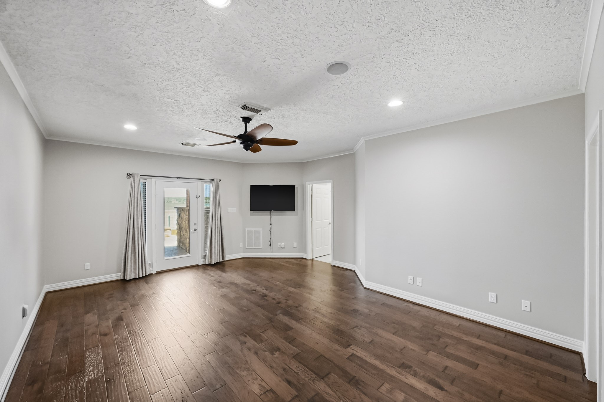 Retreat to the spacious primary suite featuring wood-look tile flooring, recessed lighting and direct access to the covered patio.