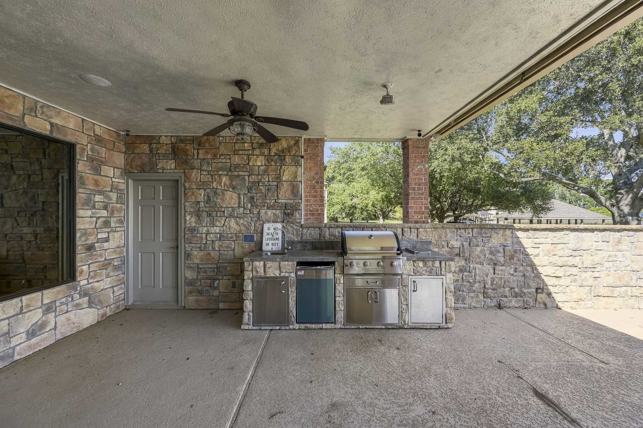 Entertain in style with an outdoor kitchen featuring a built-in gas grill, refrigerator, generous counter space and storage. Ceiling fans and stone finishes complete the covered patio.