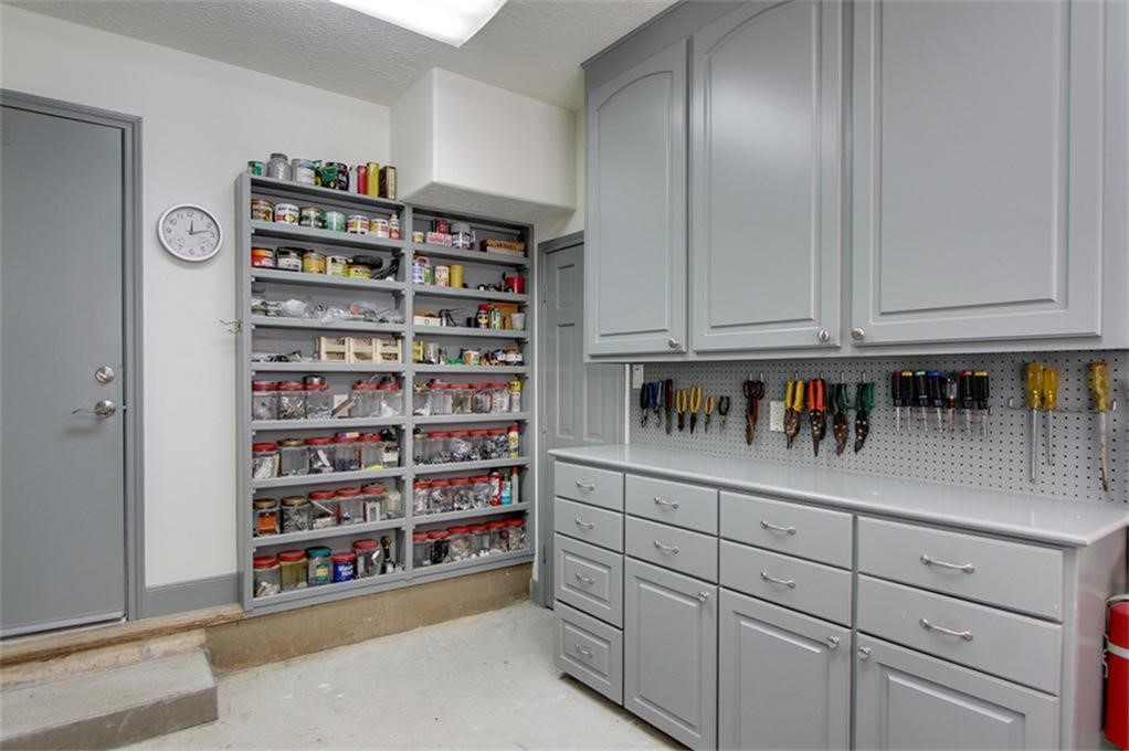 A dream space for hobbyists and DIY enthusiasts! This impressive workshop features extensive built-in cabinetry, numerous drawers, open shelving and a dedicated work surface.