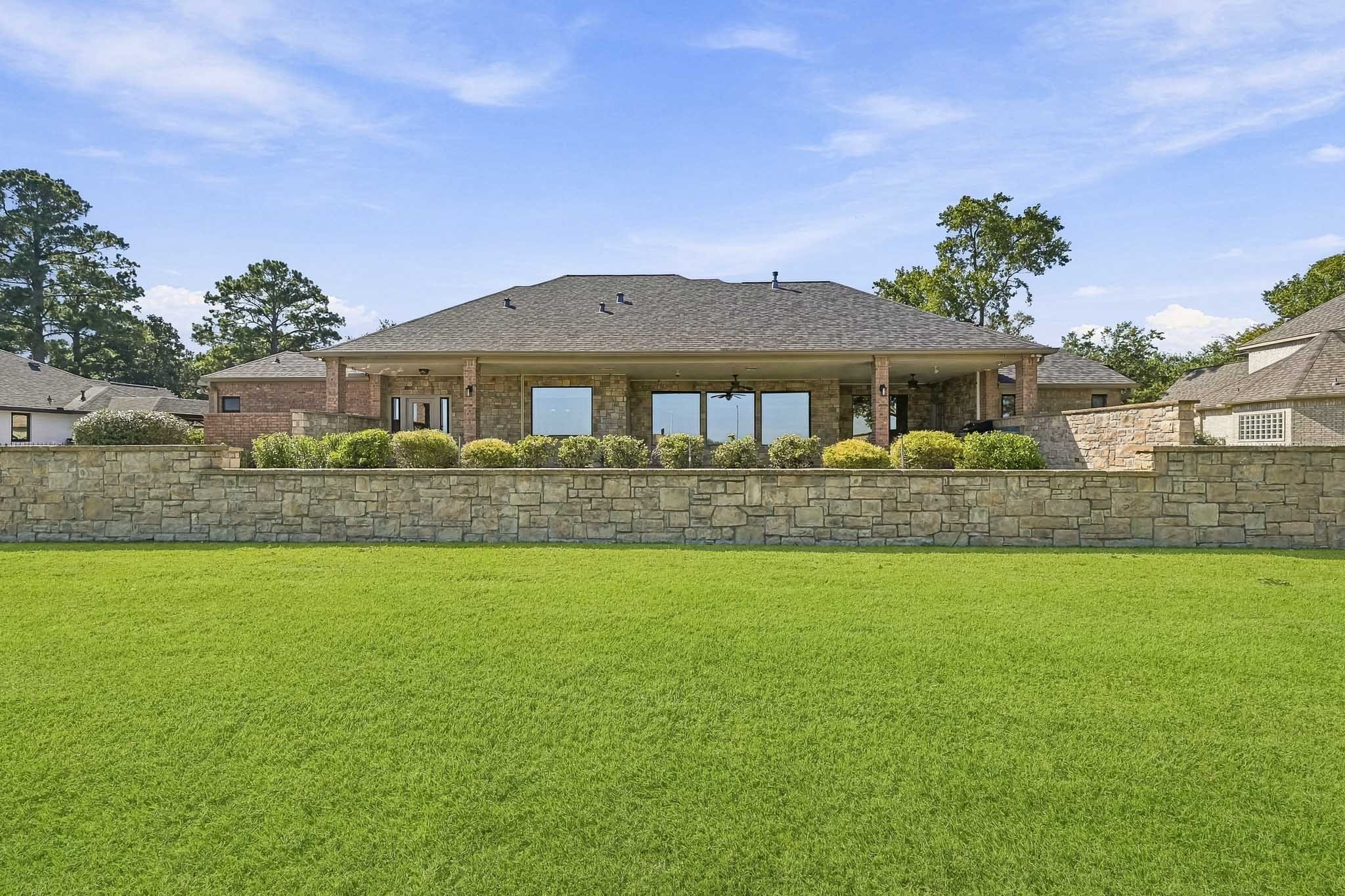 The impressive rear elevation showcases beautiful stone accents, expansive windows and the home's distinctive terraced landscaping.