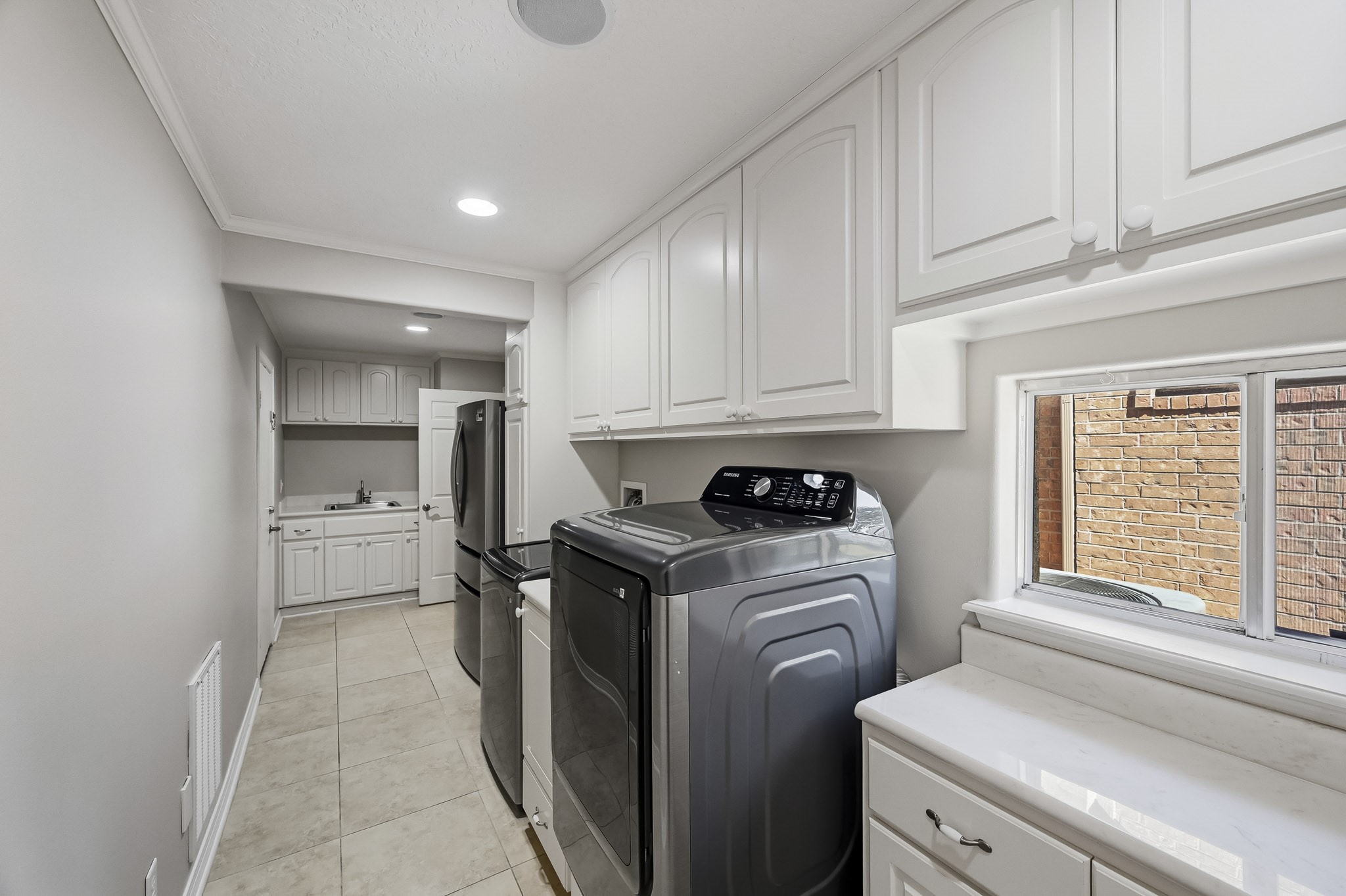 This exceptional utility room offers extensive cabinetry, generous counter space, a utility sink and room for a second refrigerator. The washer, dryer, and refrigerator can stay!
