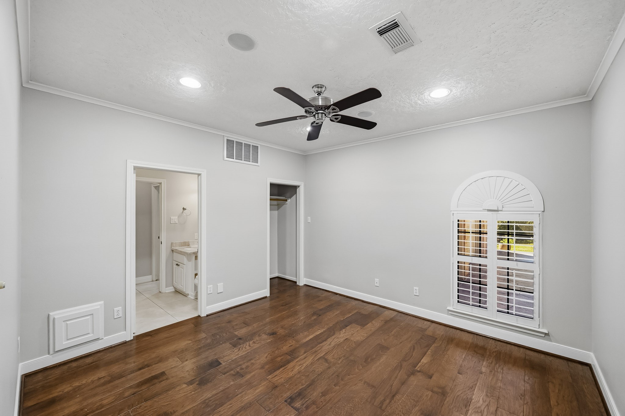 Bedroom #2. Located near the front entry, this versatile bedroom could optionally be utilized as a study. It features recessed lighting, a ceiling fan and a charming arched window with plantation shutters.