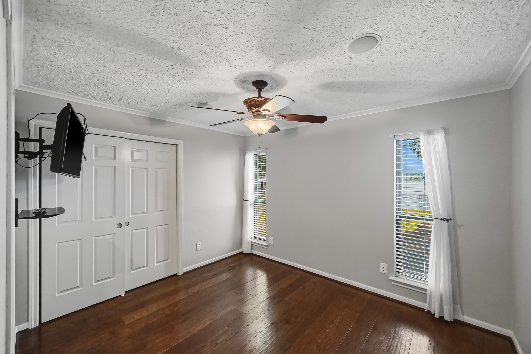 Bedroom #4 is light and bright with wood-look tile flooring, a ceiling fan and windows that welcome natural light overlooking the lake.
