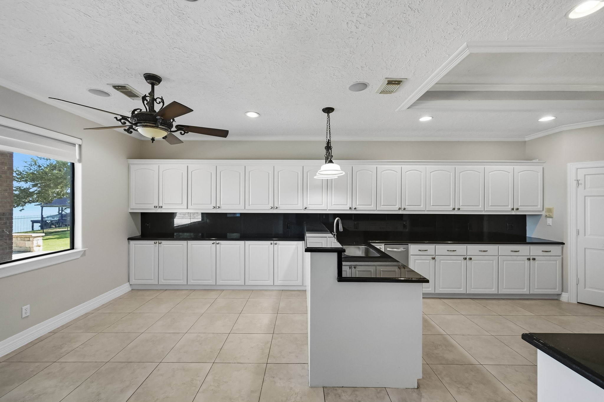 This generously sized kitchen offers extensive white cabinetry, granite countertops, a convenient prep peninsula and plenty of workspace.