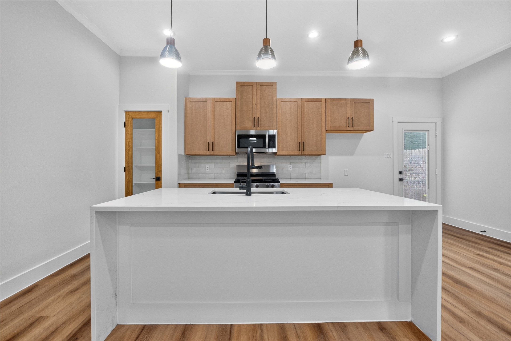 A refined kitchen anchored by a generous island, sleek stainless-steel appliances, and a spacious pantry for effortless storage--modern and functional. Refrigerator to be installed.