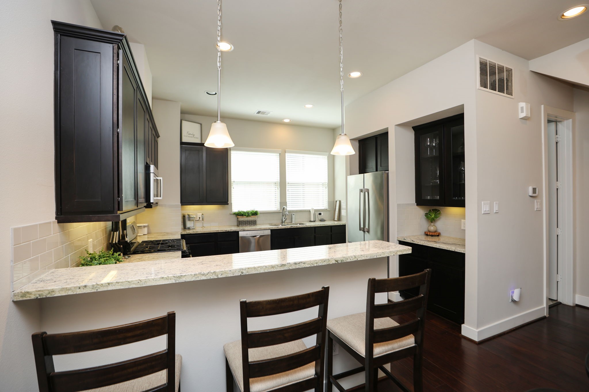 Double sided SS refrigerator, dry bar with glass cabinets, and a full pantry to the back right.