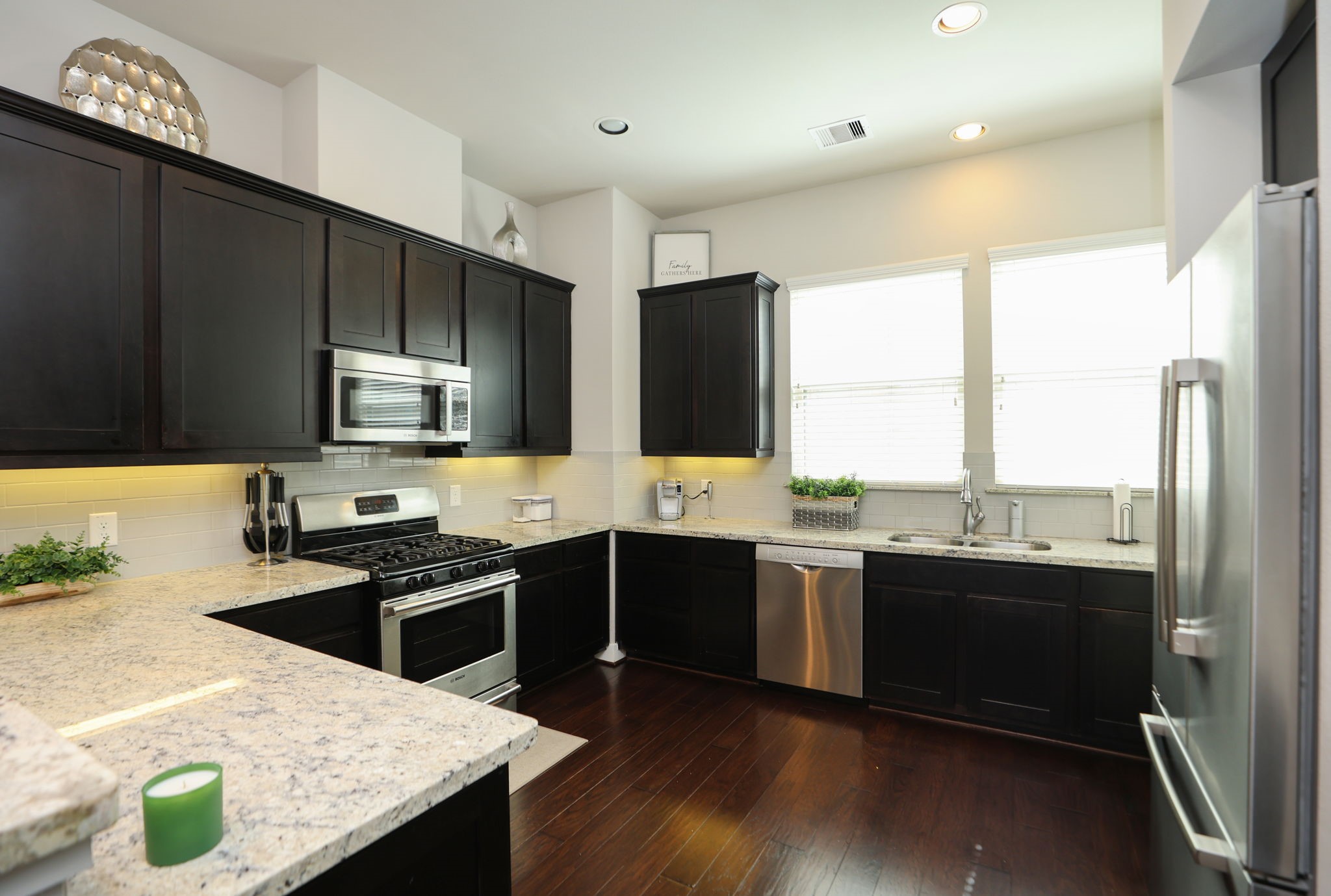 Classy dark cabinets with light granite countertops and dark wood floors give a perfectly open feel with the windows and high ceiling.