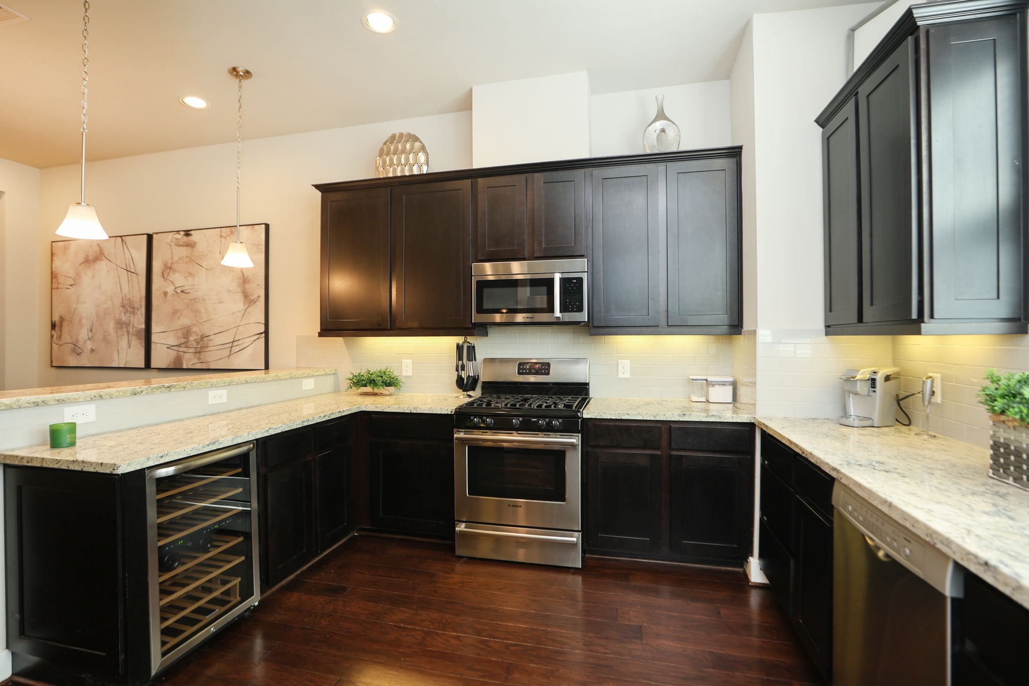 Full kitchen with gas range, microwave, wine fridge, pendant lights and beautiful hardwood floors. High ceilings have can inset lights for optional brightness.