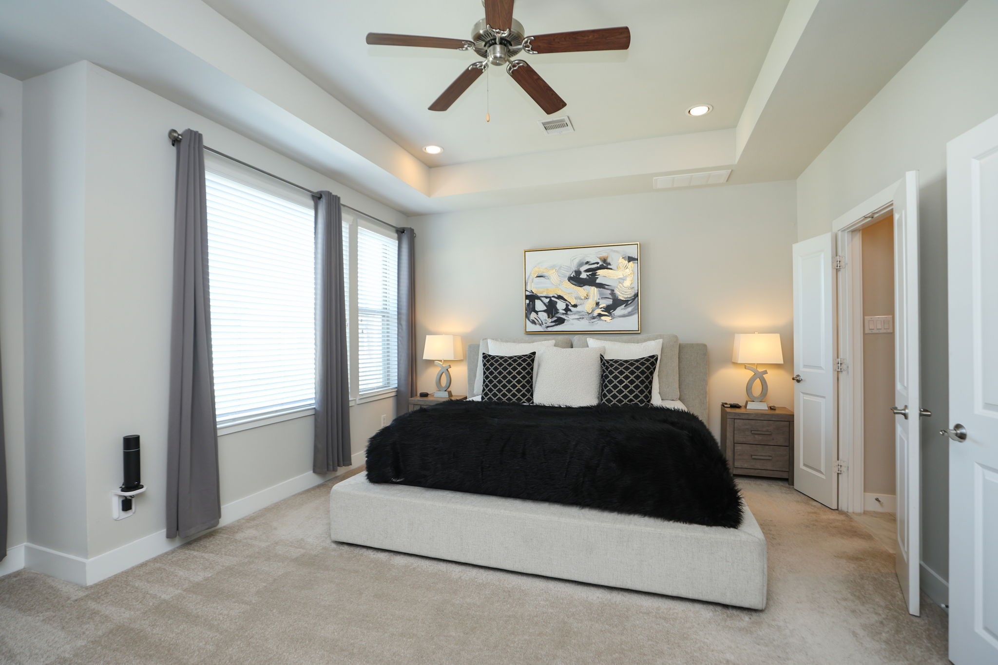 Peaceful primary suite with high recessed ceiling, fan and room for any furniture (king sized bed present here).