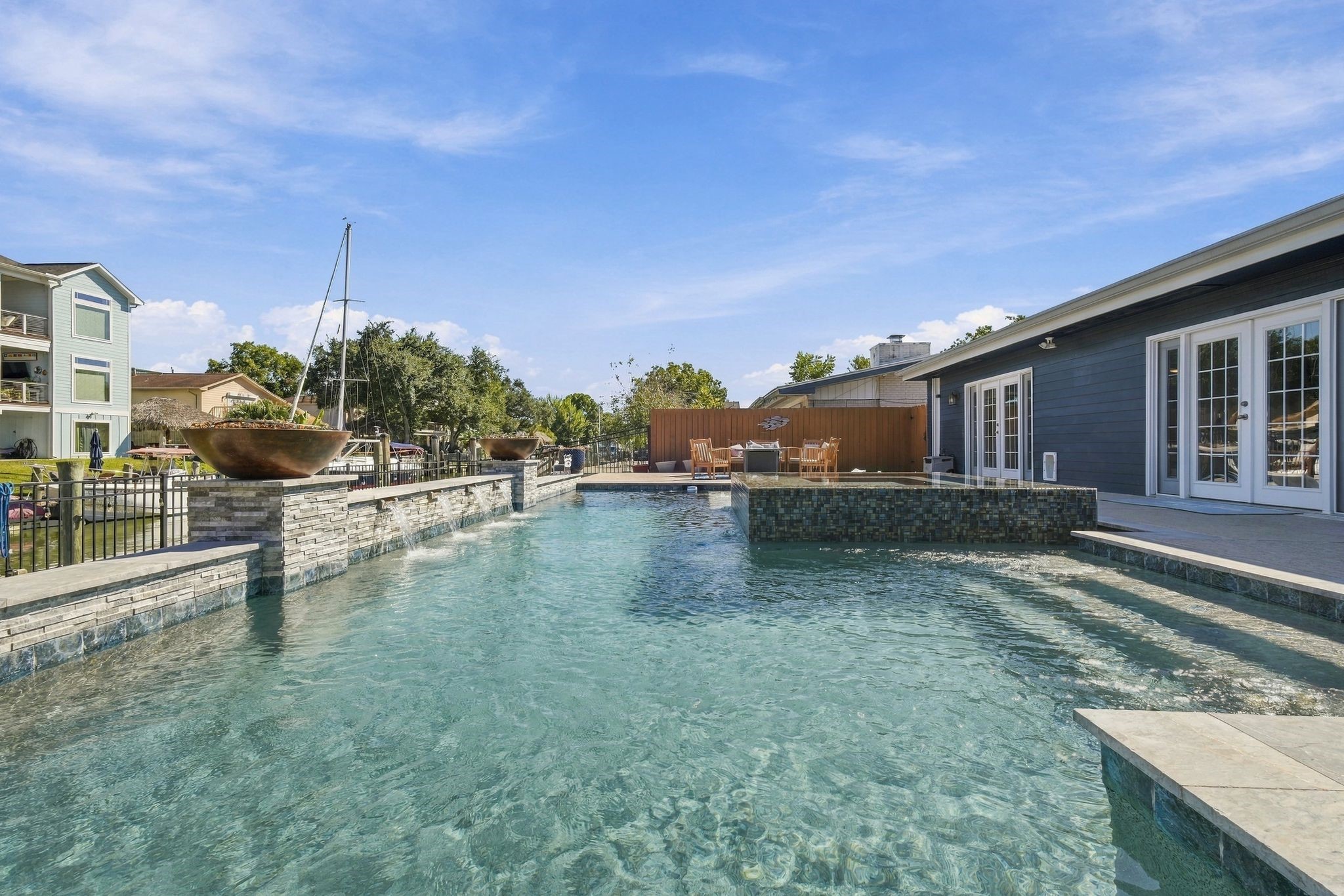 Luxurious outdoor oasis featuring a sparkling pool with a stone-accented edge, complemented by a spacious patio and modern landscaping, perfect for relaxing and entertaining.
