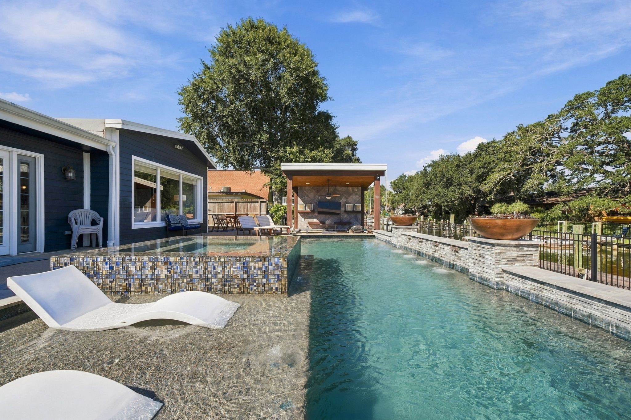 Experience luxury outdoor living with this stunning pool area, featuring a sleek modern design, sun loungers, and a covered outdoor kitchen. Experience luxury outdoor living with this stunning pool area, featuring a sleek modern design, sun loungers, and a covered outdoor kitchen.