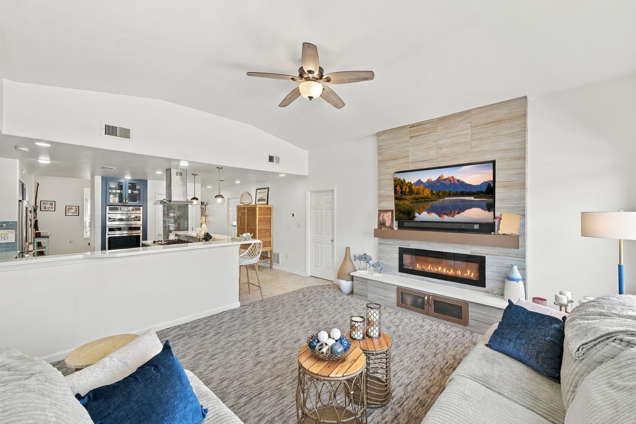 Spacious living area featuring a modern open-concept design, with a cozy electric fireplace and a wall-mounted TV.