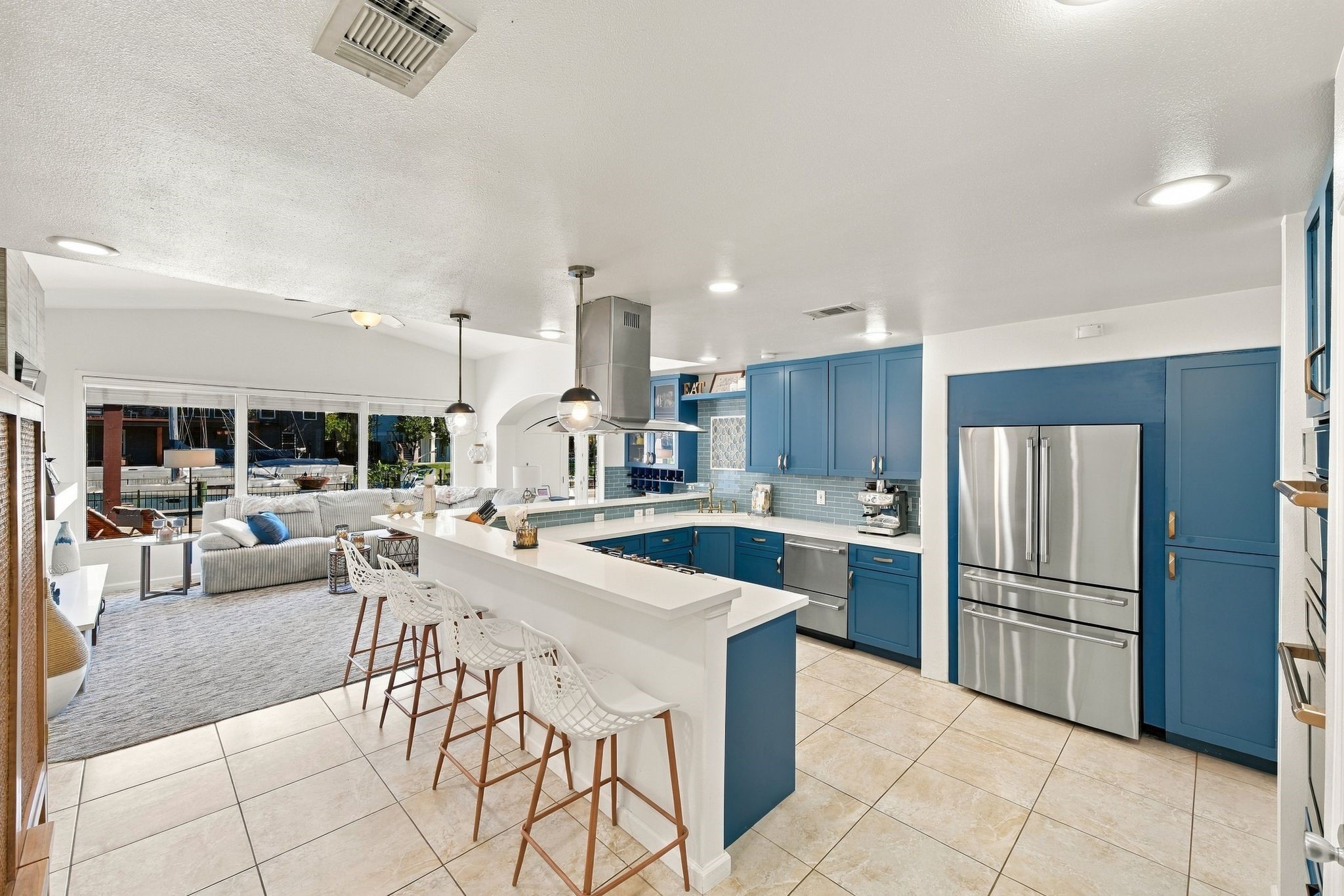 Spacious kitchen featuring sleek blue cabinetry, modern stainless steel appliances, and a convenient breakfast bar with stylish seating.