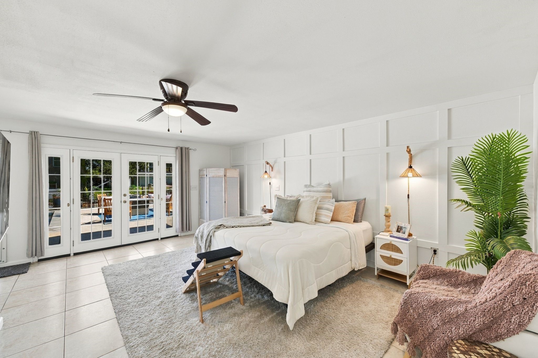 The spacious first-floor primary suite offers a peaceful waterfront retreat, featuring elegant French doors that open to a sunlit patio with beautiful water views. Two generous walk-in closets provide ample storage, adding comfort and convenience to this inviting private sanctuary.