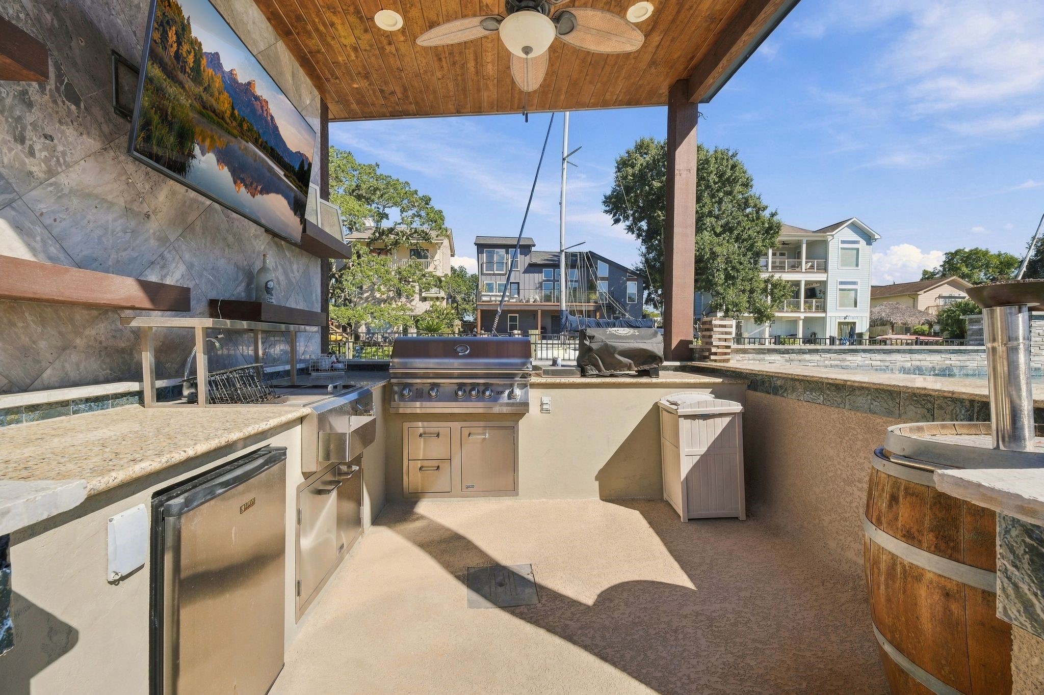 Experience outdoor living at its finest with this stylish outdoor kitchen, featuring sleek stainless steel appliances, a built-in grill, a mounted TV, and a swim up bar. Experience outdoor living at its finest with this stylish outdoor kitchen, featuring sleek stainless steel appliances, a built-in grill, a mounted TV, and a swim up bar.