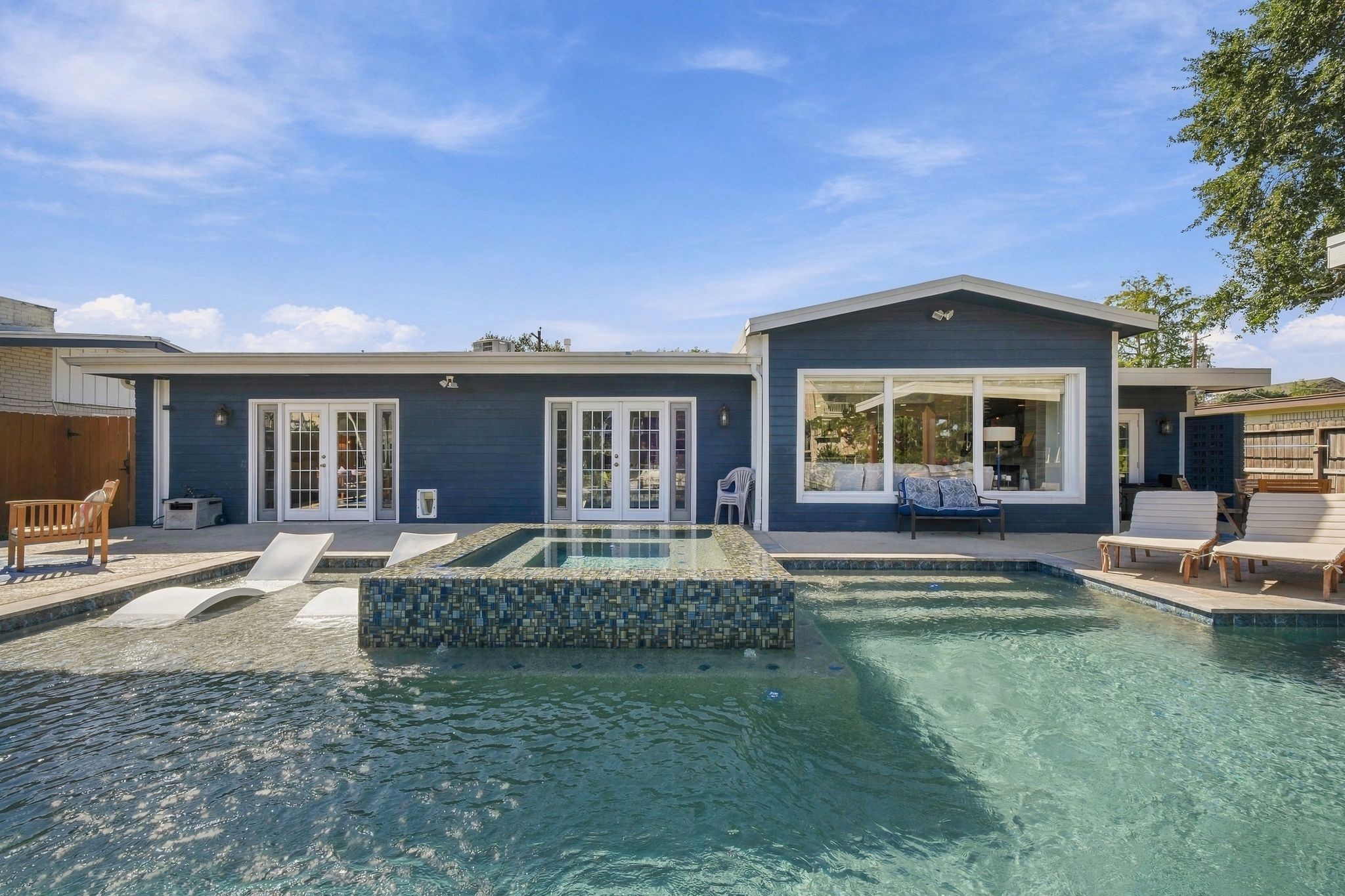 Modern home with a stunning backyard retreat, featuring a sparkling pool, integrated spa, and stylish patio area, and outdoor kitchen, perfect for relaxation and entertainment. Modern home with a stunning backyard retreat, featuring a sparkling pool, integrated spa, and stylish patio area, and outdoor kitchen, perfect for relaxation and entertainment.