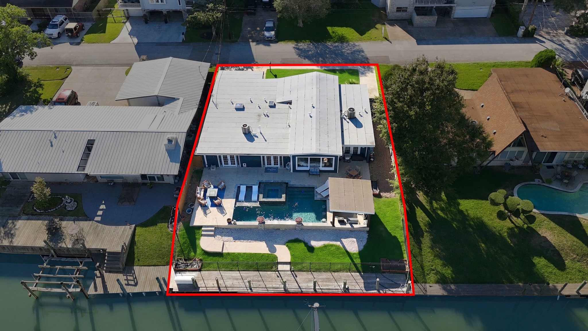 Spacious waterfront property featuring a modern outdoor oasis with a pool, shaded patio, and direct access to the canal.