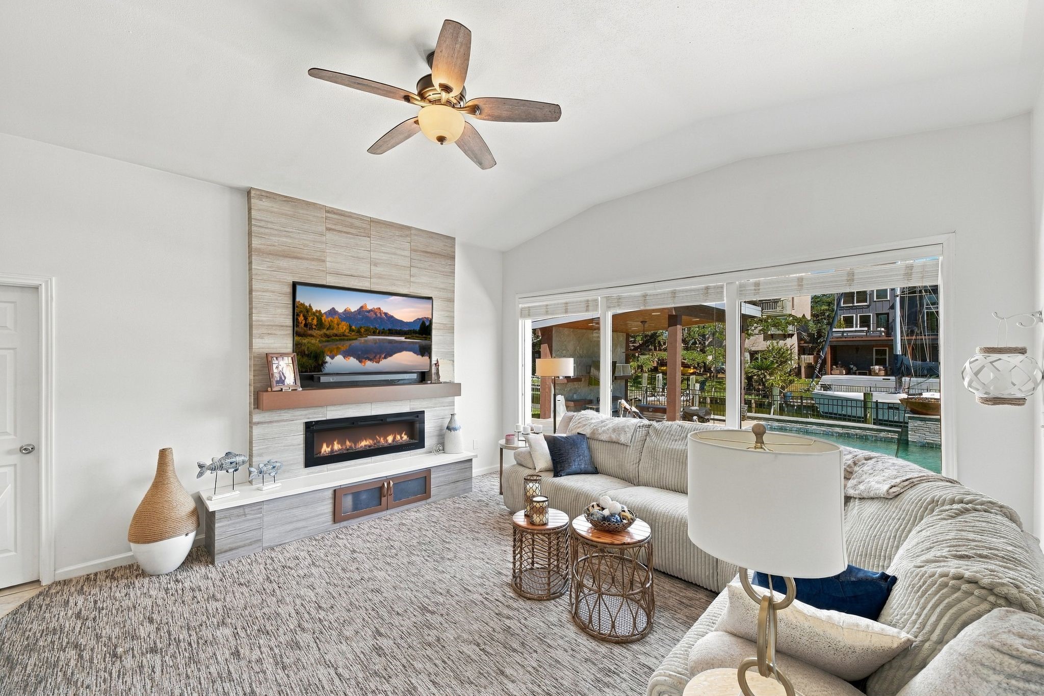 The living room features a modern fireplace, cozy sectional seating, and expansive windows offering stunning waterfront views.