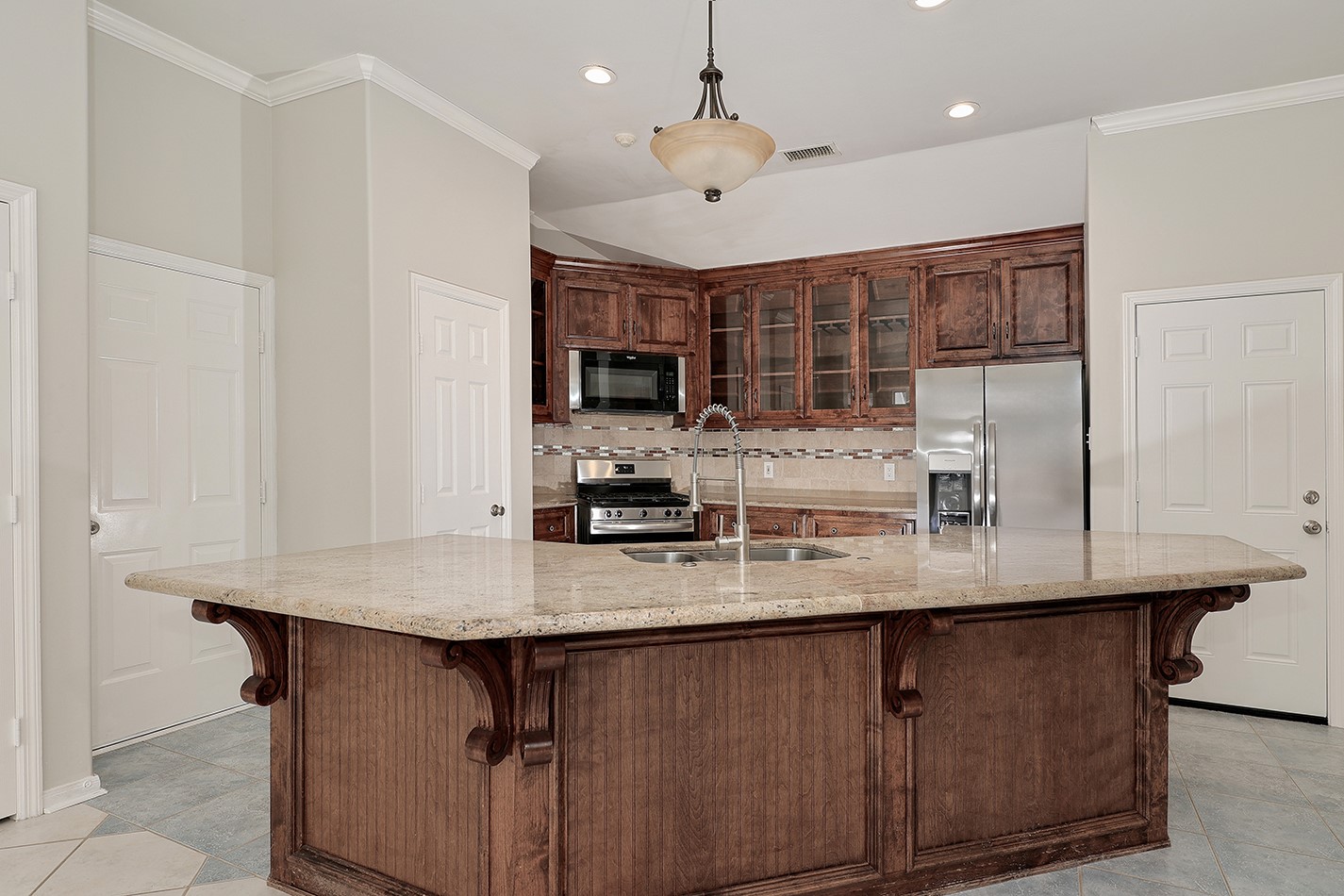 This modern kitchen features a spacious island with a granite countertop, elegant wood cabinetry, stainless steel appliances, and ample storage. Ideal for cooking and entertaining.