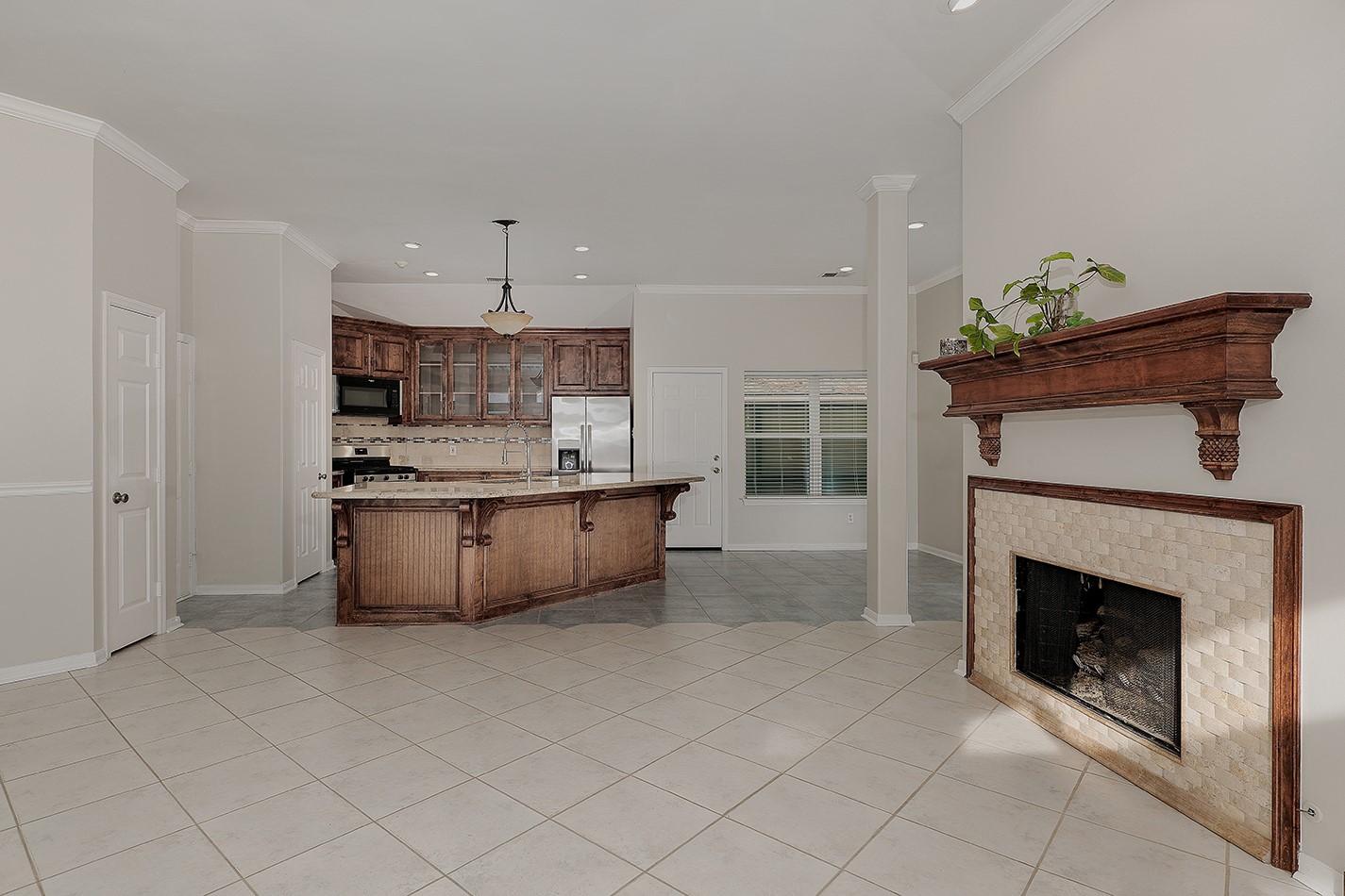 View from the family room into the kitchen and dining. Neutral tile flooring throughout enhances the bright and airy feel.