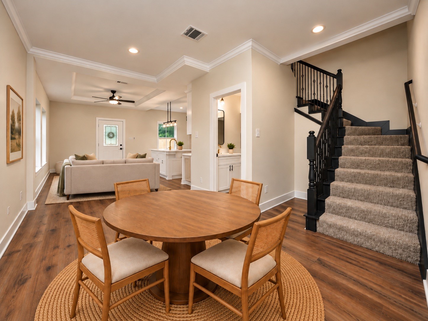Step inside to an inviting open-concept layout featuring 9-foot ceilings, luxury vinyl plank flooring, crown molding, oversized baseboards, and recessed lighting. The dining area flows naturally into the family room and kitchen, while the staircase adds architectural character. | Virtually Staged