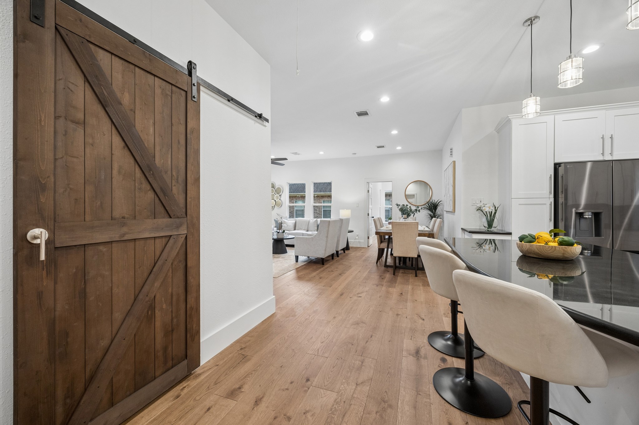 Elegant open-concept living area featuring a modern kitchen with sleek bar seating, a rustic sliding barn door, and a spacious dining area perfect for entertaining.