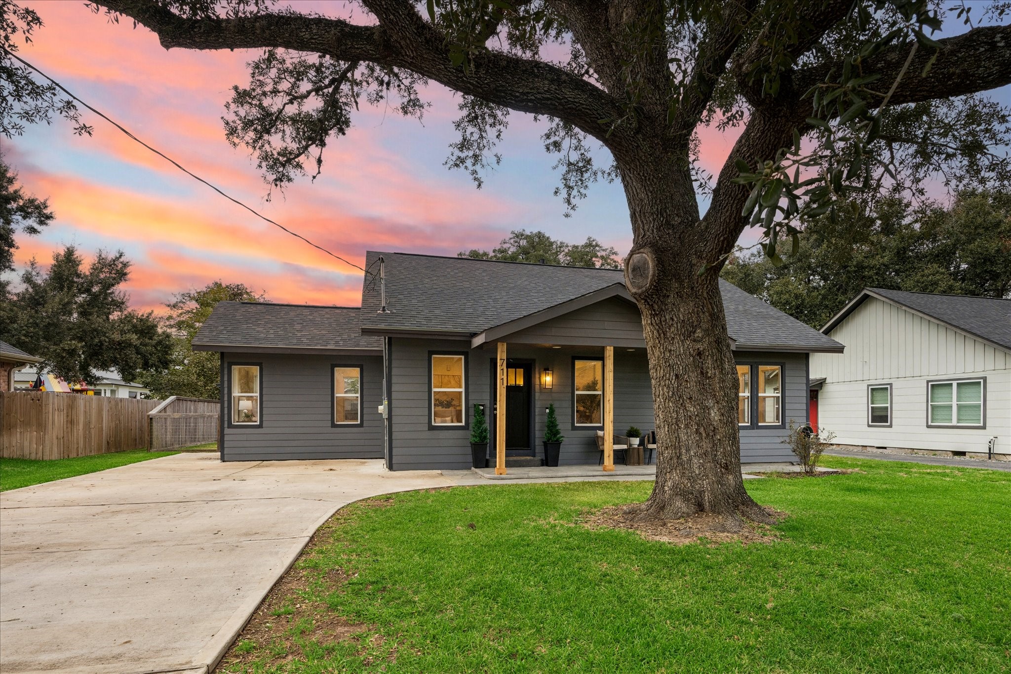 Charming home with modern accents features a sleek black door, elegant lighting, cedar beam posts, and covered sitting area. Charming home with modern accents features a sleek black door, elegant lighting, cedar beam posts, and covered sitting area.