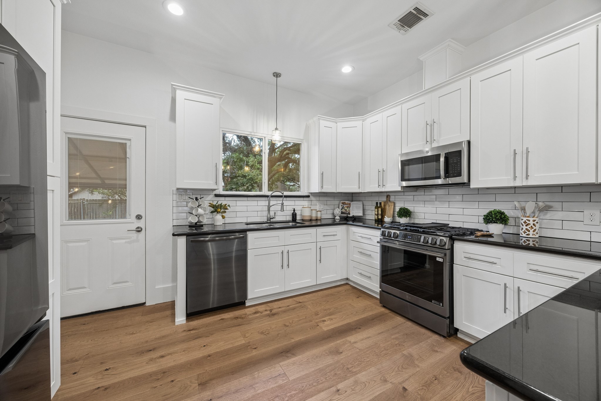 Bright and modern kitchen with sleek white cabinetry, stainless steel appliances, and elegant subway tile backsplash, complemented by warm hardwood floors.