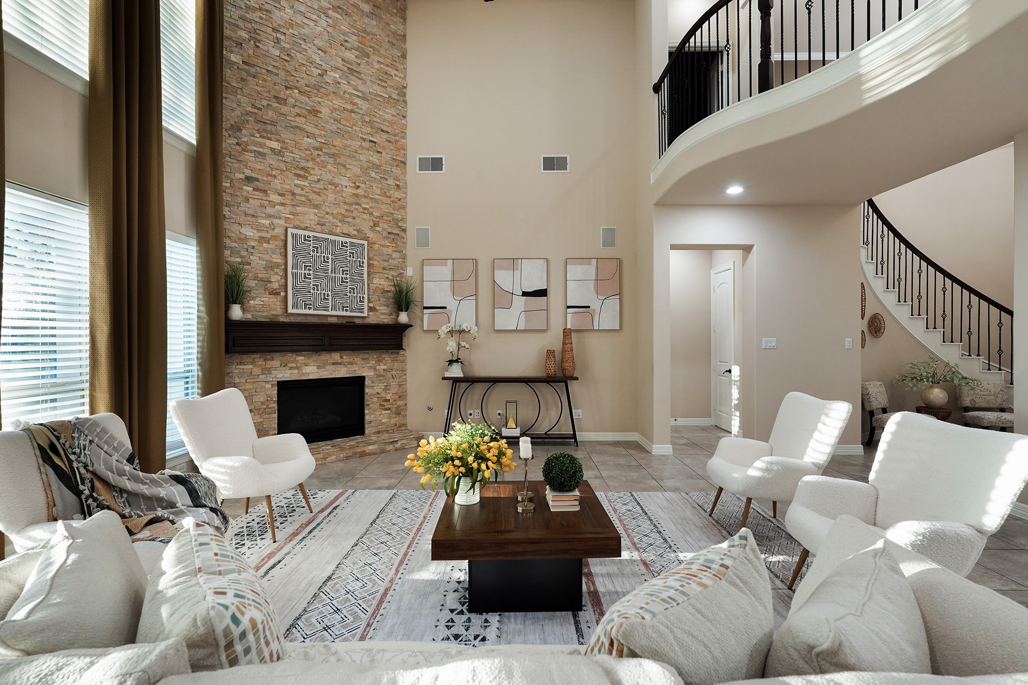This living room features a high ceiling, modern decor, and a stone accent wall with a fireplace. Large windows allow natural light to brighten the space. A curved staircase adds elegance, and the open layout is perfect for entertaining.