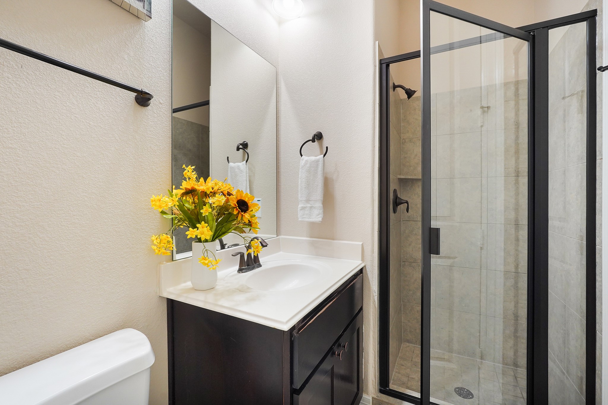 FIRST Flr-2nd bedroom down: This bathroom features a modern glass-enclosed shower, and a sleek vanity with a white countertop. It has a neutral color palette and efficient use of space.