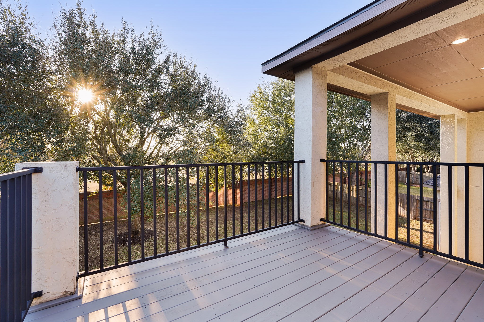 Large balcony off Game Room with modern railing, offering scenic views of a tree-lined backyard. Perfect for relaxing and enjoying the outdoors.