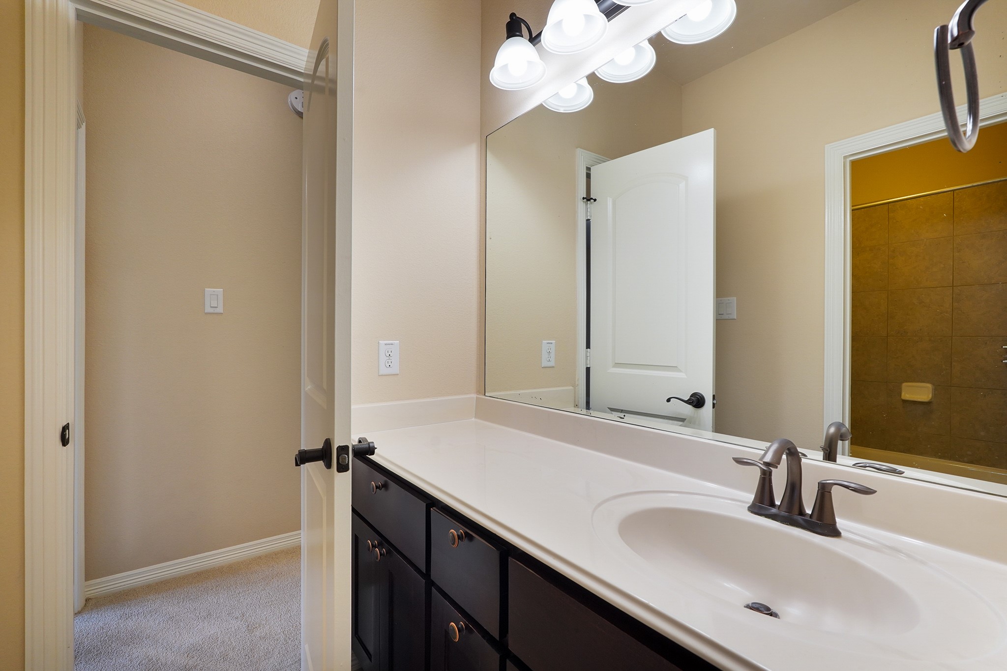 SECOND Flr-Bath#3: Bright bathroom with a large mirror, modern fixtures, and ample counter space. It features a dark wood vanity and connects to a carpeted hallway.