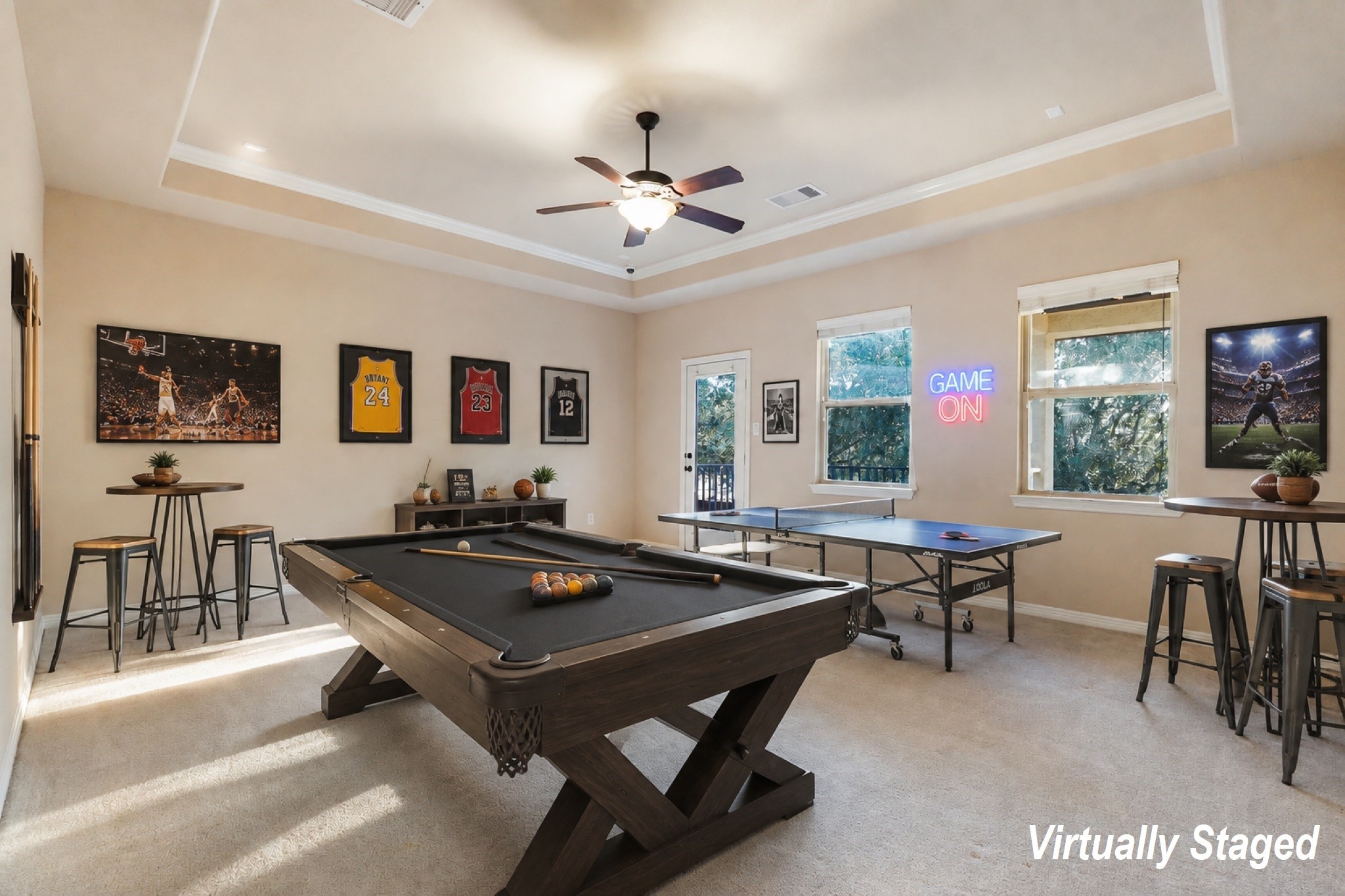 *Virtually Staged* SECOND Flr-Game Room:This spacious, carpeted room features neutral walls, a ceiling fan, and a tray ceiling design. Natural light streams through two large windows and a glass door, which opens to a small balcony with tree views.